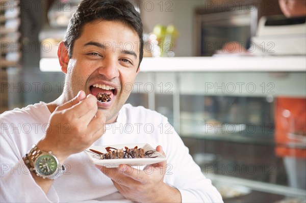 Hispanic man eating dessert in cafe