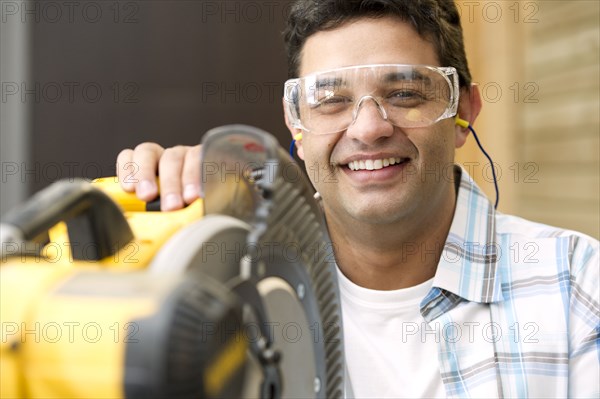 Hispanic carpenter standing with saw