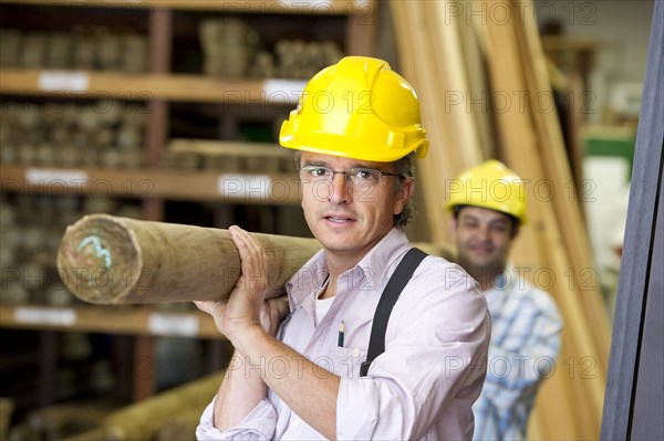 Hispanic carpenters carrying lumber