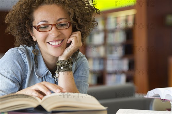 Hispanic woman reading book in library