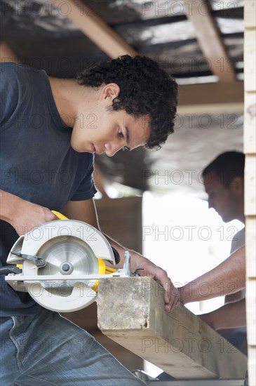 Hispanic carpenter sawing lumber