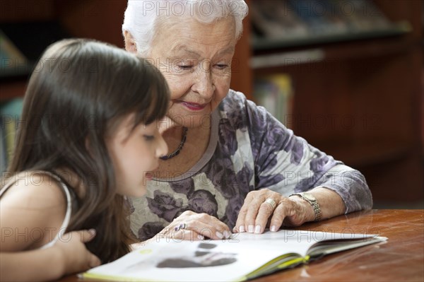 Hispanic grandmother reading book to granddaughter