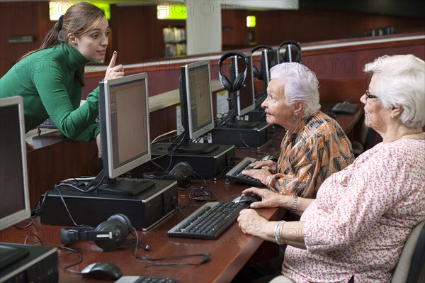 Hispanic teacher helping senior students in computer lab