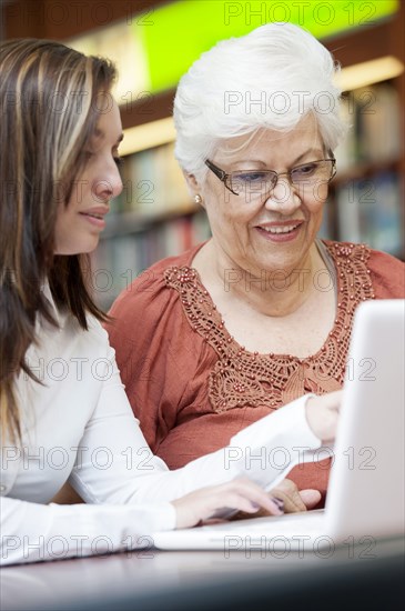 Hispanic teacher helping senior student with laptop