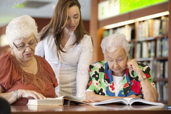 Hispanic teacher helping senior students in library