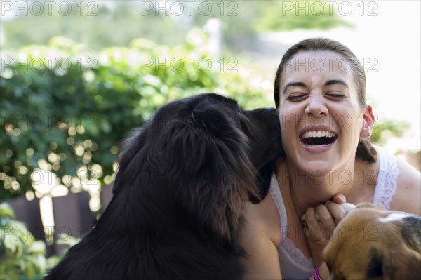 Hispanic woman playing with dogs