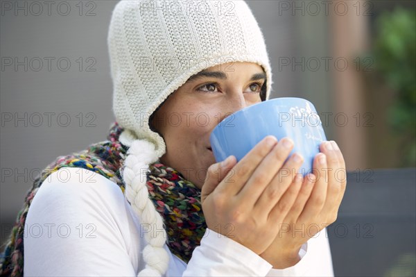 Hispanic woman drinking coffee outdoors