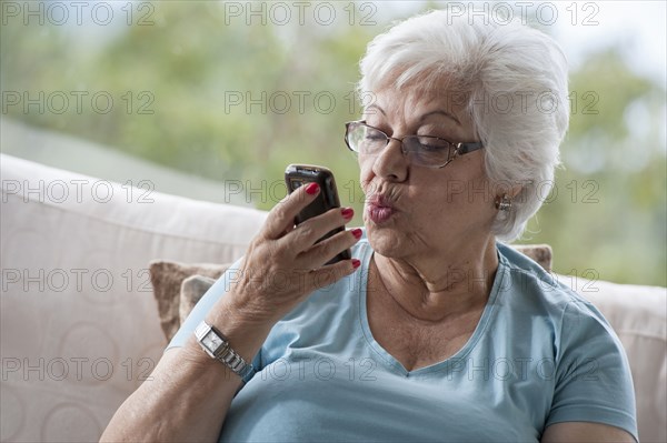 Hispanic woman making kissy face at cell phone