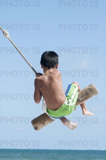 Hispanic boy playing on swing outdoors