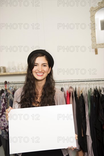 Hispanic woman holding blank card in shop