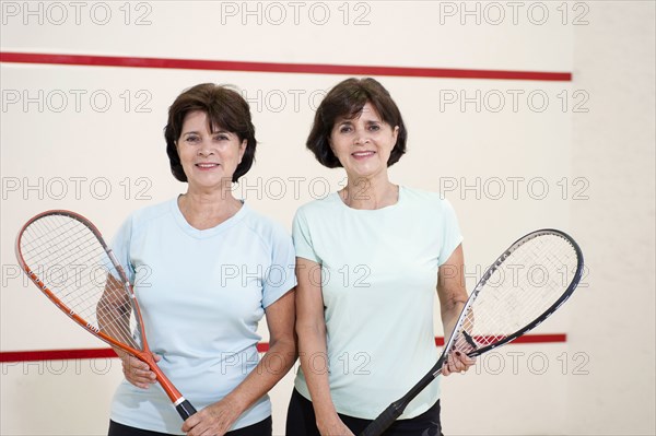 Senior Hispanic twins holding squash rackets