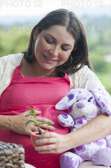 Pregnant Hispanic woman seedling in pot
