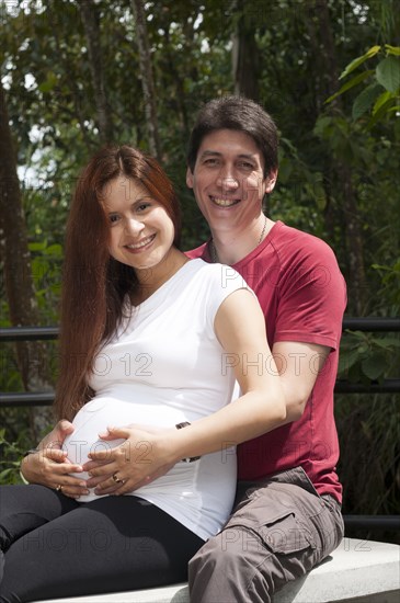 Mixed race expectant couple hugging outdoors