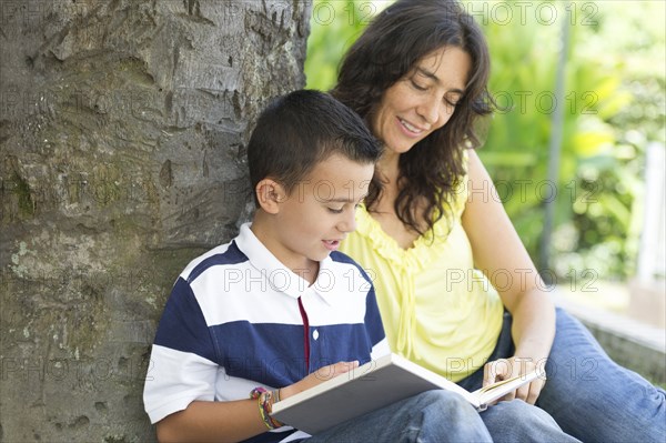 Hispanic mother and son reading book