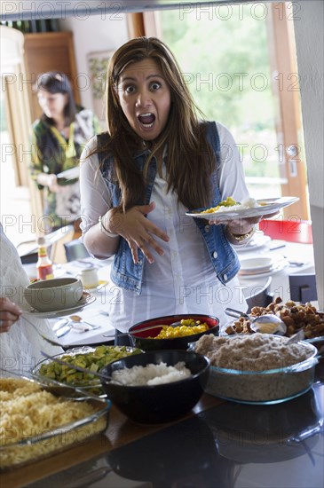 Woman gasping and holding plate of food at party