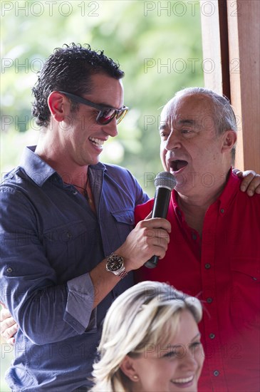 Grandfather and grandson talking into microphone at family reunion