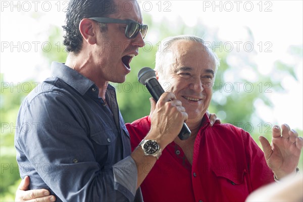 Grandfather and grandson talking into microphone at family reunion