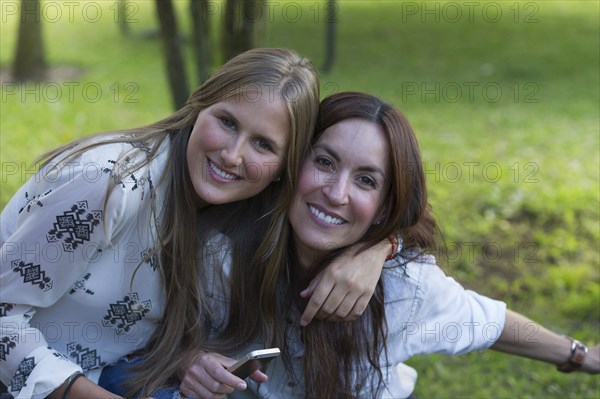 Smiling Hispanic women hugging outdoors