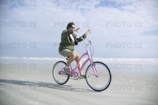 Senior woman riding bicycle on beach