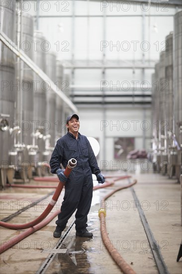 Chilean man holding industrial hose at winery