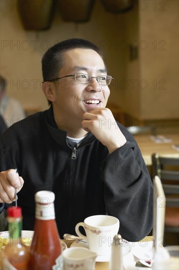 Asian man eating in restaurant