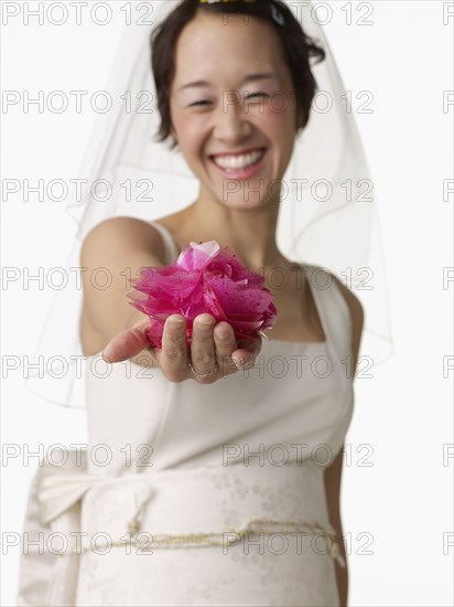 Asian woman in wedding dress holding flower