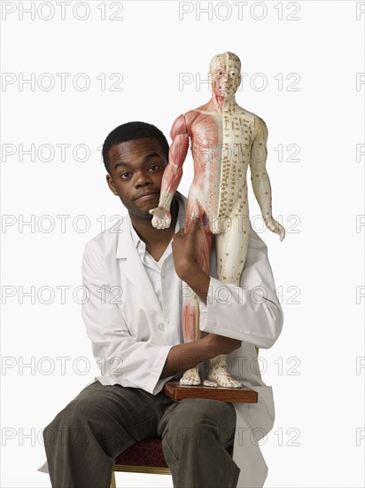 African chiropractor holding anatomical model