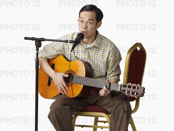 Asian man playing guitar and singing