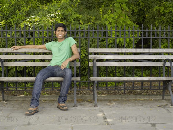 Indian man relaxing on park bench