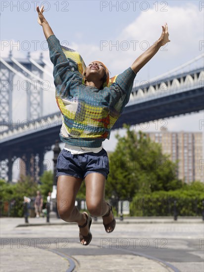 African woman jumping in mid-air in urban setting