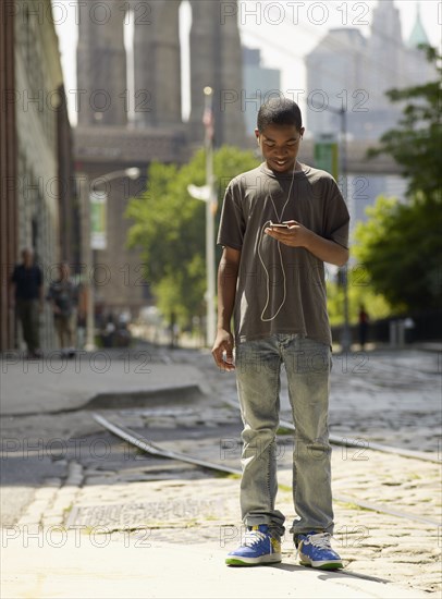 African boy listening to mp3 player in urban setting