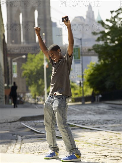 African boy listening to mp3 player in urban setting