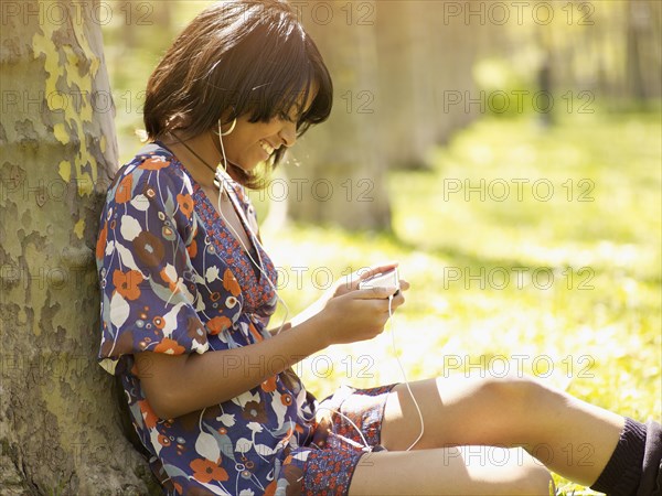 Hispanic woman listening to mp3 player in park