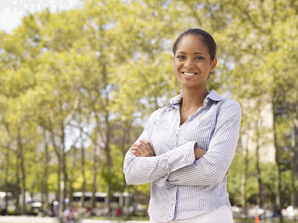 Mixed race woman with arms crossed in park