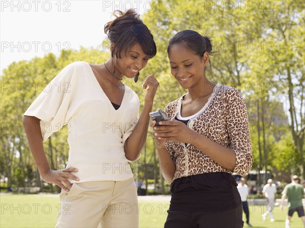 Woman looking at friend's cell phone