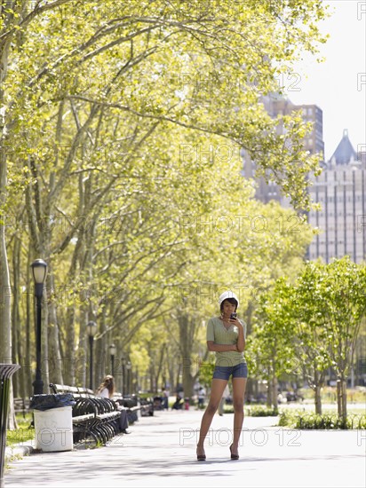 Hispanic woman text messaging on cell phone in park