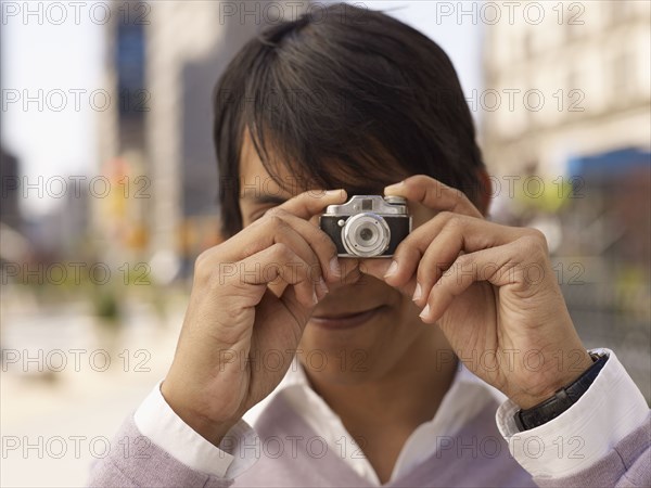 Indian man taking photograph with miniature camera