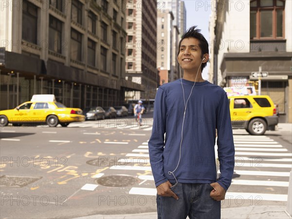 Indian man on city street listening to mp3 player