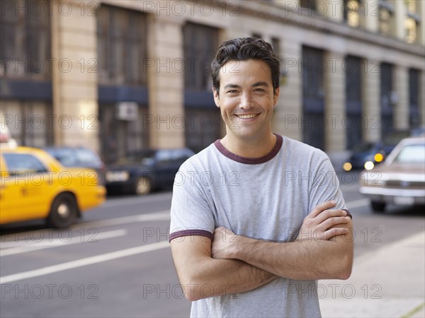 Man with arms crossed on city street