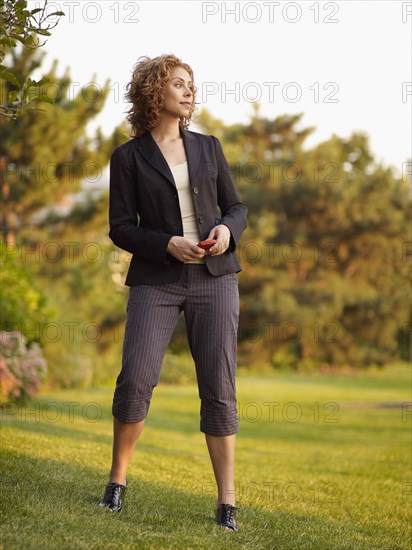 Mixed race woman holding cell phone in park