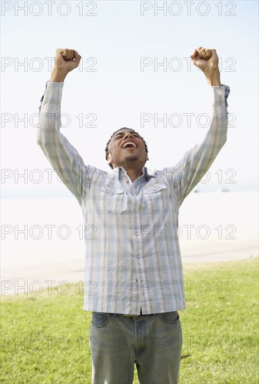 Young mixed race man with arms raised