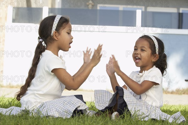 Young mixed race girls sitting and playing pat-a-cake