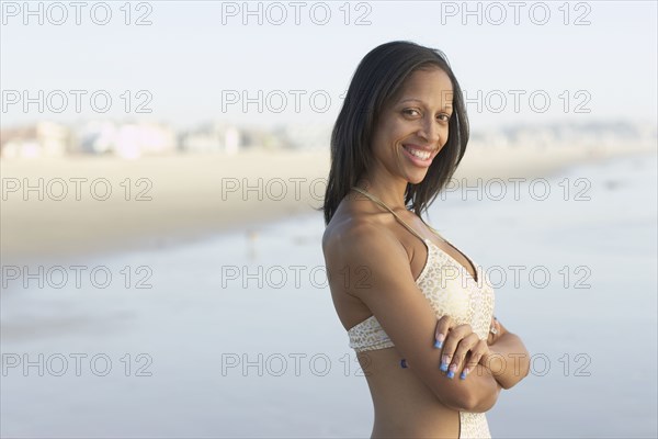 Mixed race woman with arms crossed at beach