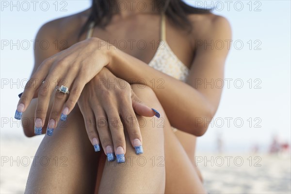 Midsection of mixed race woman sitting on beach