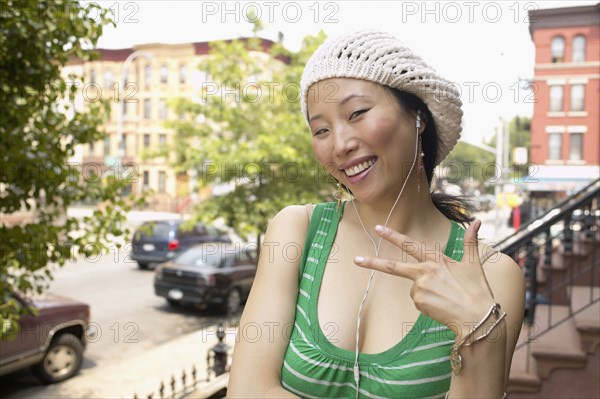 Asian woman on front steps listening to music