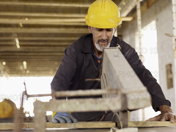 Hispanic worker using saw at construction site