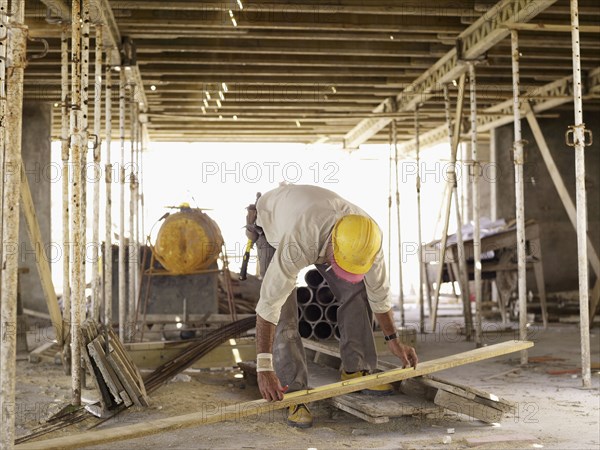 Hispanic worker measuring lumber at construction site