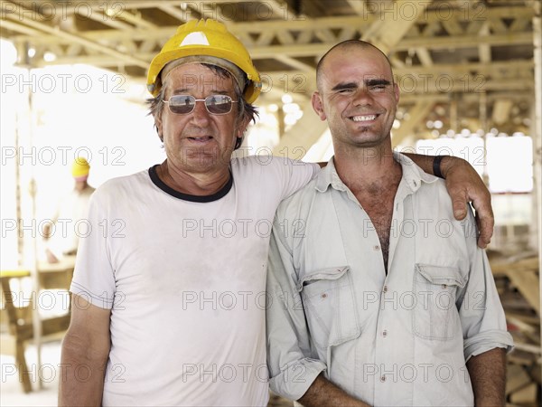 Hispanic workers hugging construction site