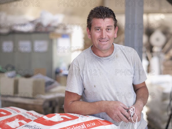 Hispanic worker holding bag in factory warehouse