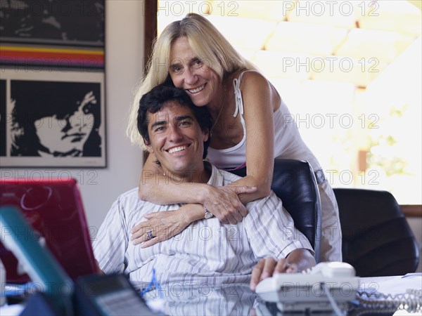 Hispanic woman hugging son at desk